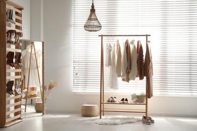 Photo of Modern dressing room interior with racks of stylish women's clothes and shoes