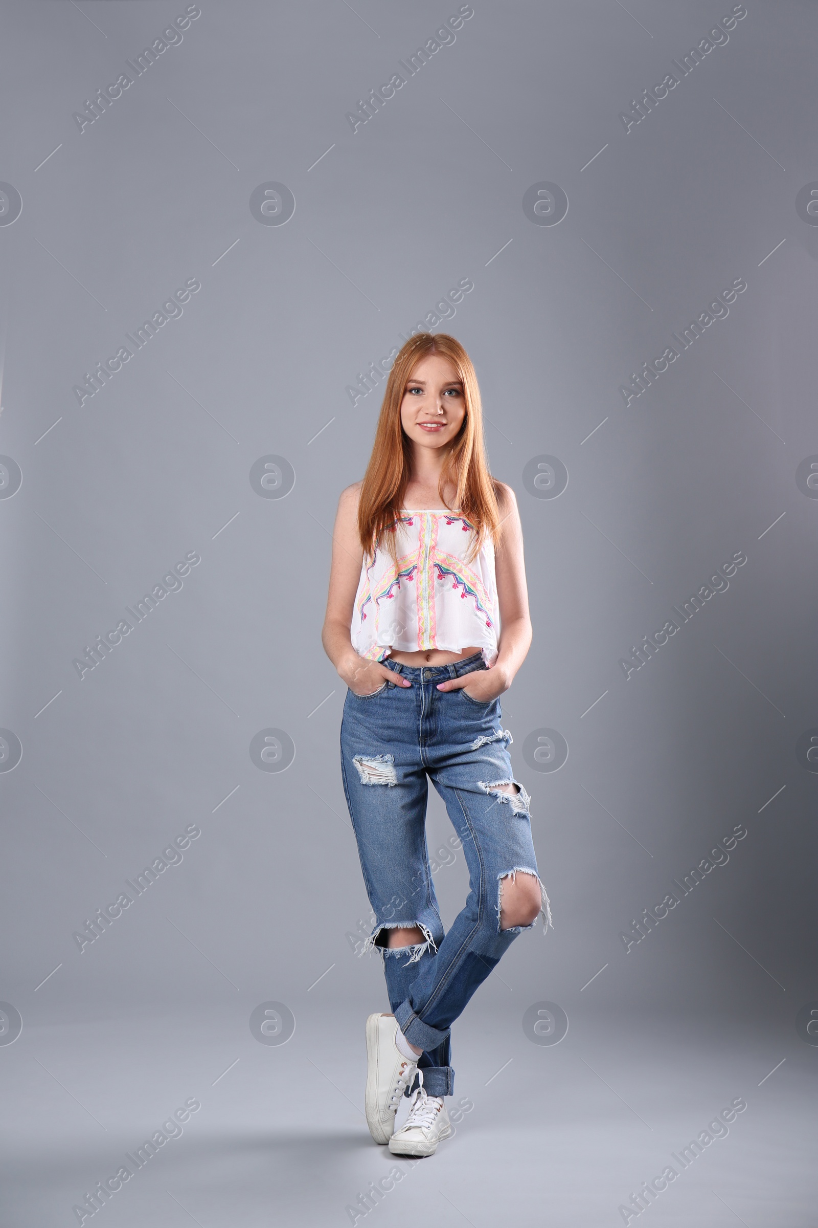 Photo of Young woman in stylish jeans on grey background