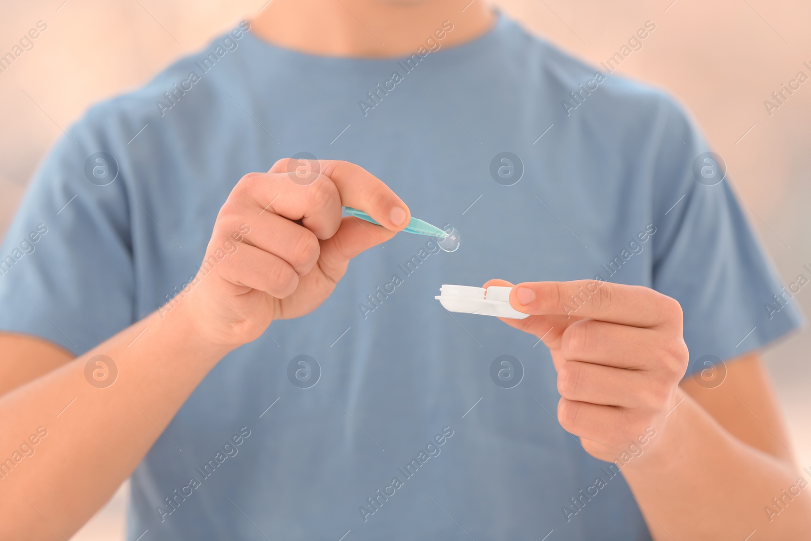 Photo of Teenage boy taking contact lens from container, closeup of hands