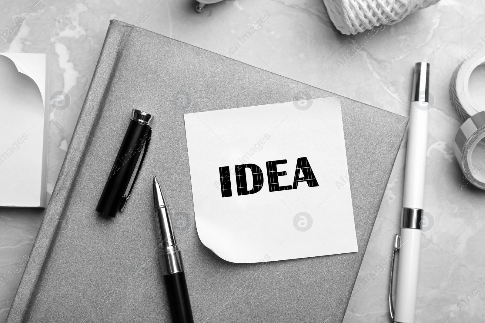 Image of Note with word IDEA and stationery on grey marble table, flat lay