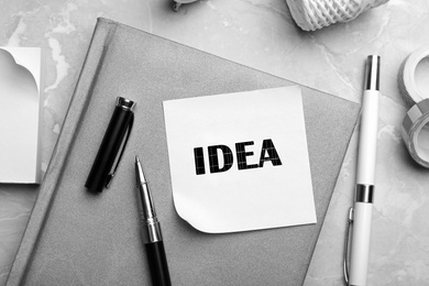 Image of Note with word IDEA and stationery on grey marble table, flat lay