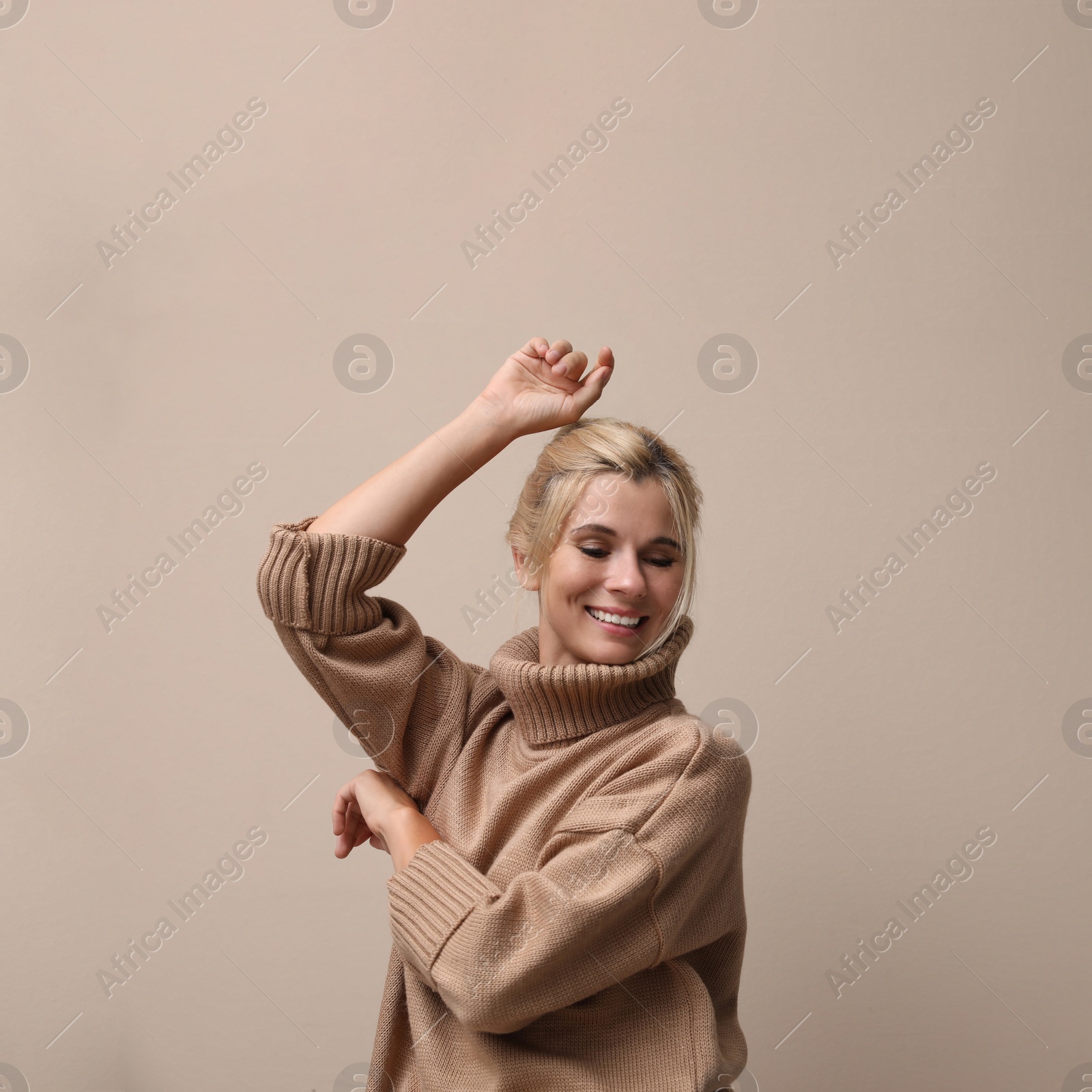 Photo of Happy woman in stylish sweater on beige background