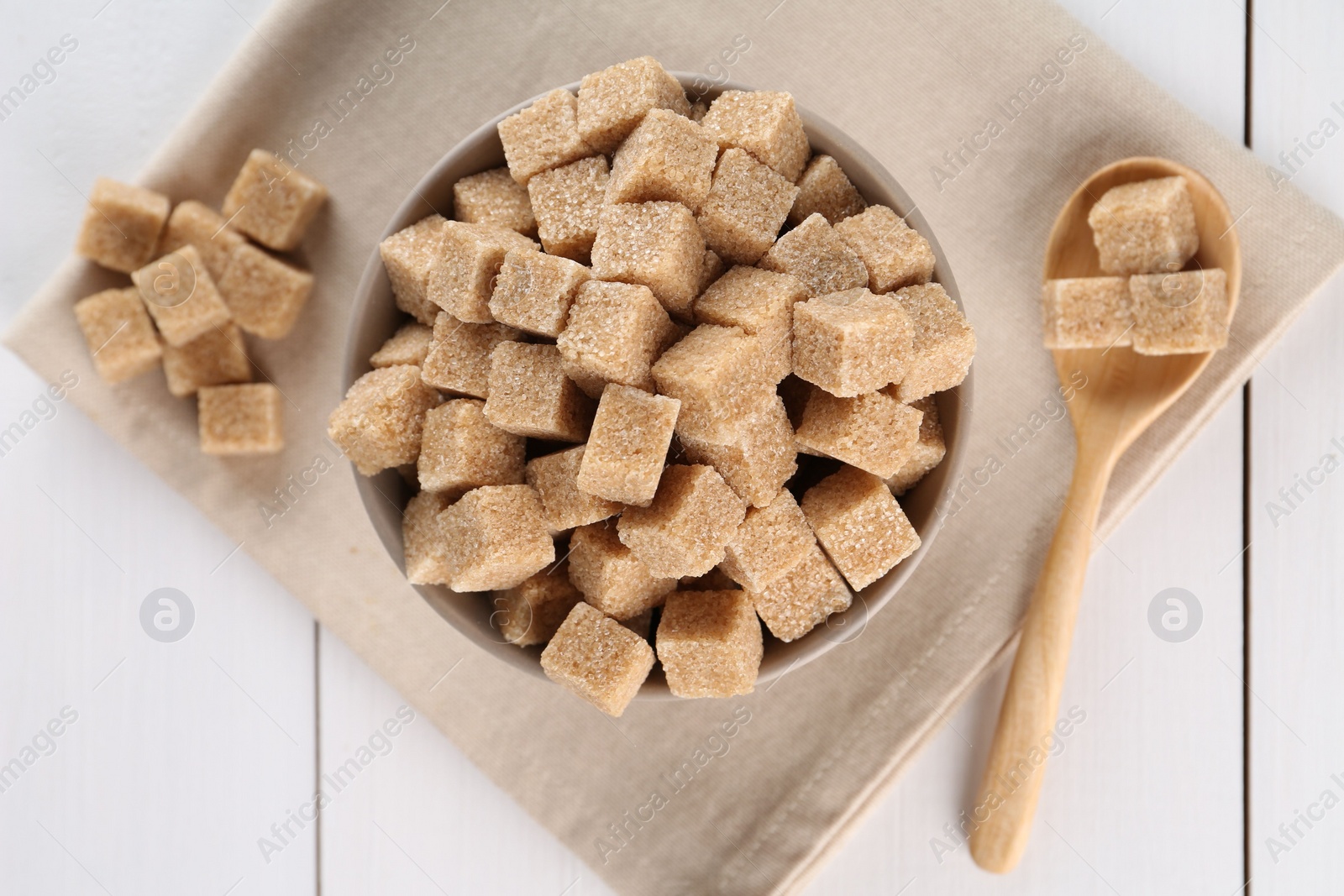 Photo of Brown sugar cubes on white wooden table, flat lay