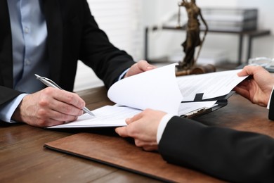 Man signing document in lawyer's office, closeup