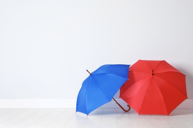 Photo of Beautiful open umbrellas on floor near white wall with space for design