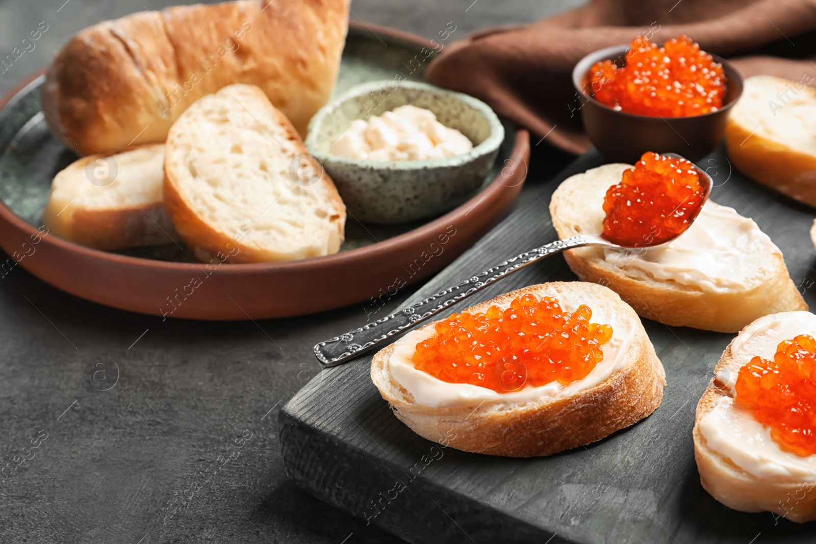 Photo of Delicious sandwiches with red caviar on wooden board