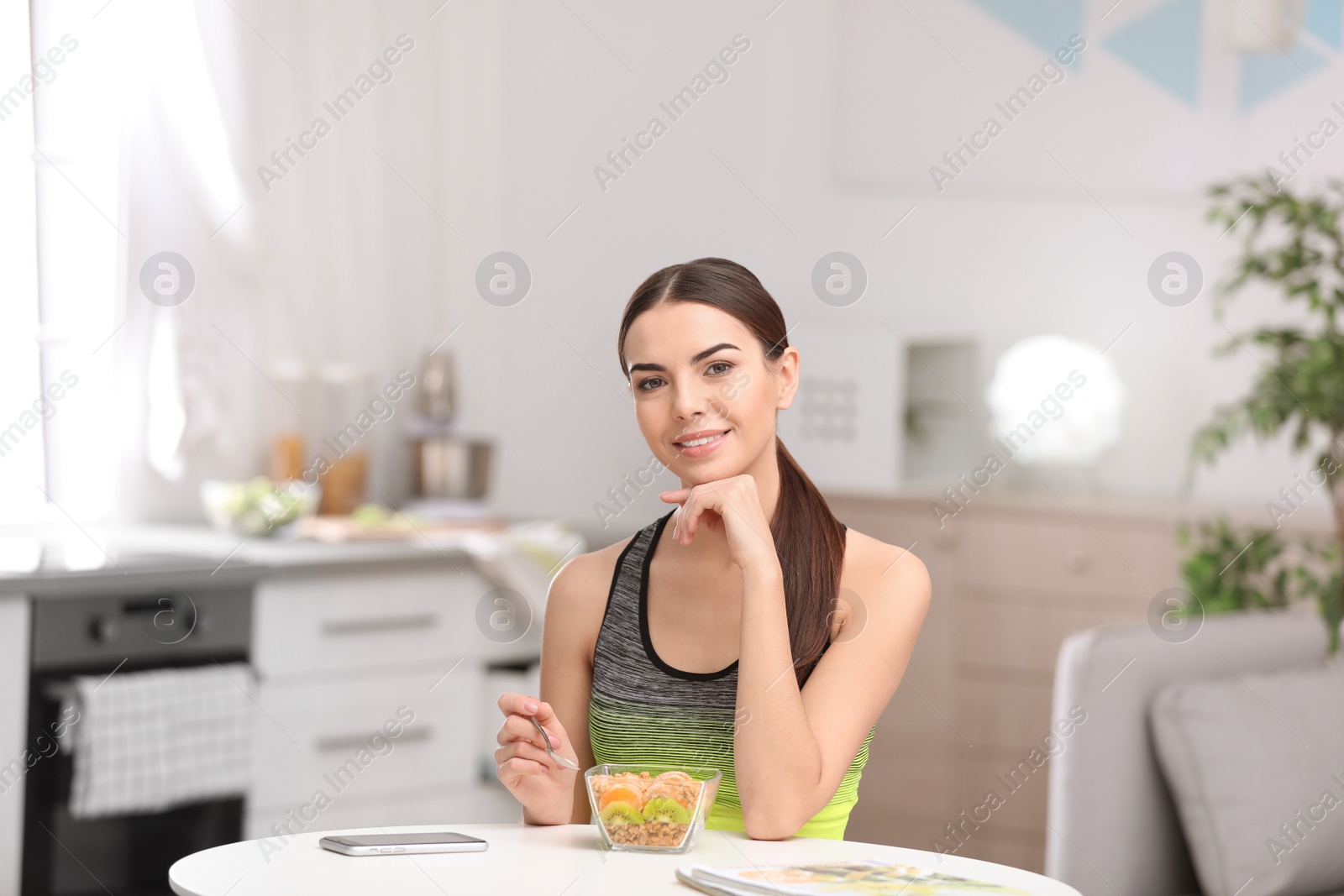 Photo of Young woman in fitness clothes having healthy breakfast at home