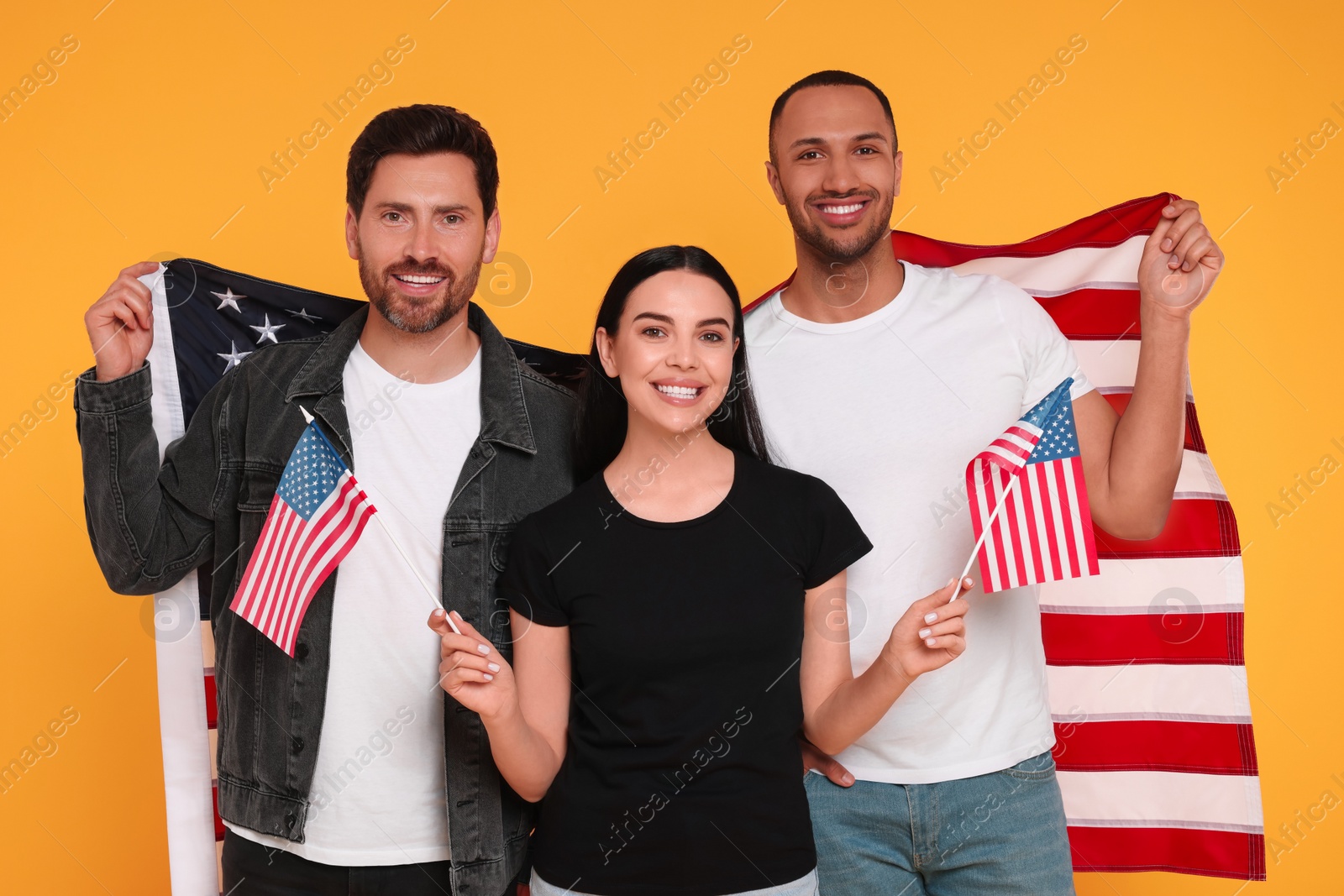 Photo of 4th of July - Independence Day of USA. Happy friends with American flags on yellow background