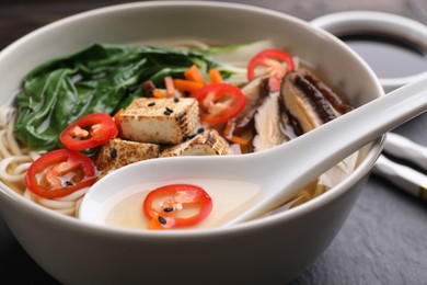 Photo of Bowl of vegetarian ramen and spoon on table, closeup