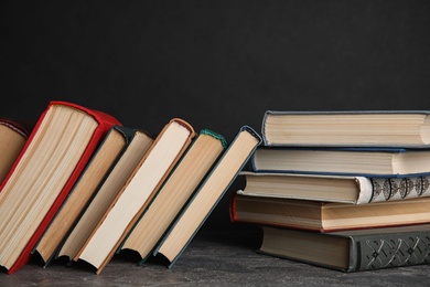 Photo of Stack of hardcover books on grey stone table against black background