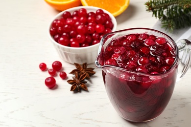 Photo of Fresh cranberry sauce in pitcher on white table, space for text