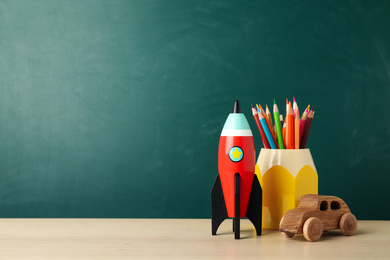 Bright toy rocket and school supplies on wooden desk. Space for text