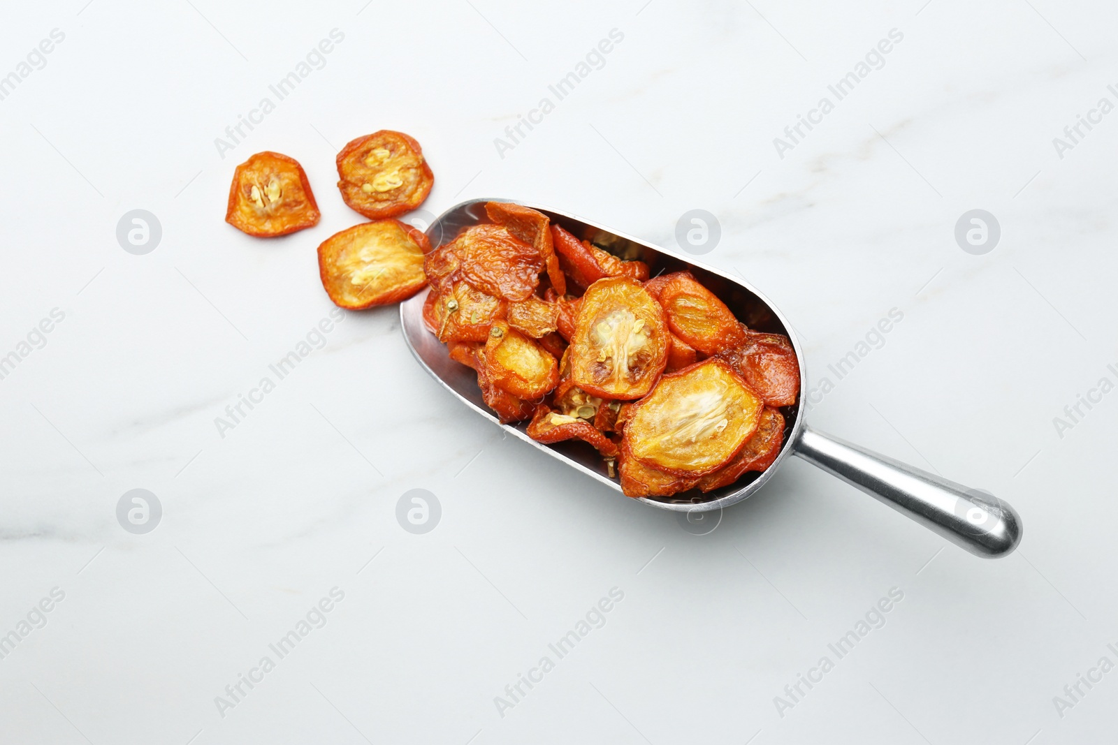 Photo of Scoop with cut dried kumquat fruits on white marble table, flat lay