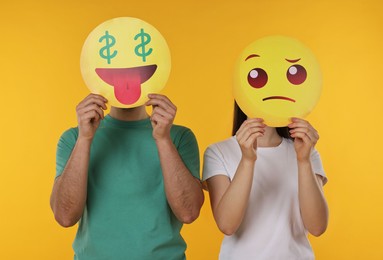 People covering faces with emoticons on yellow background