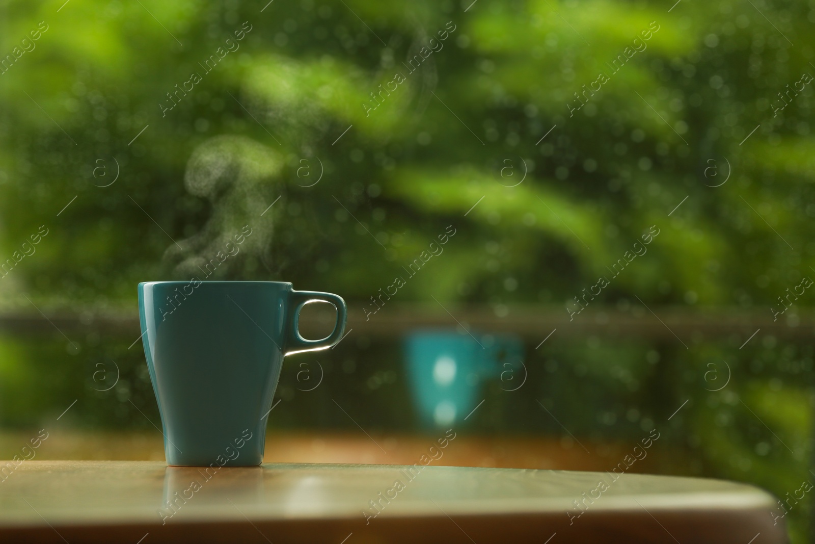 Photo of Cup of hot drink on wooden table against blurred background, space for text