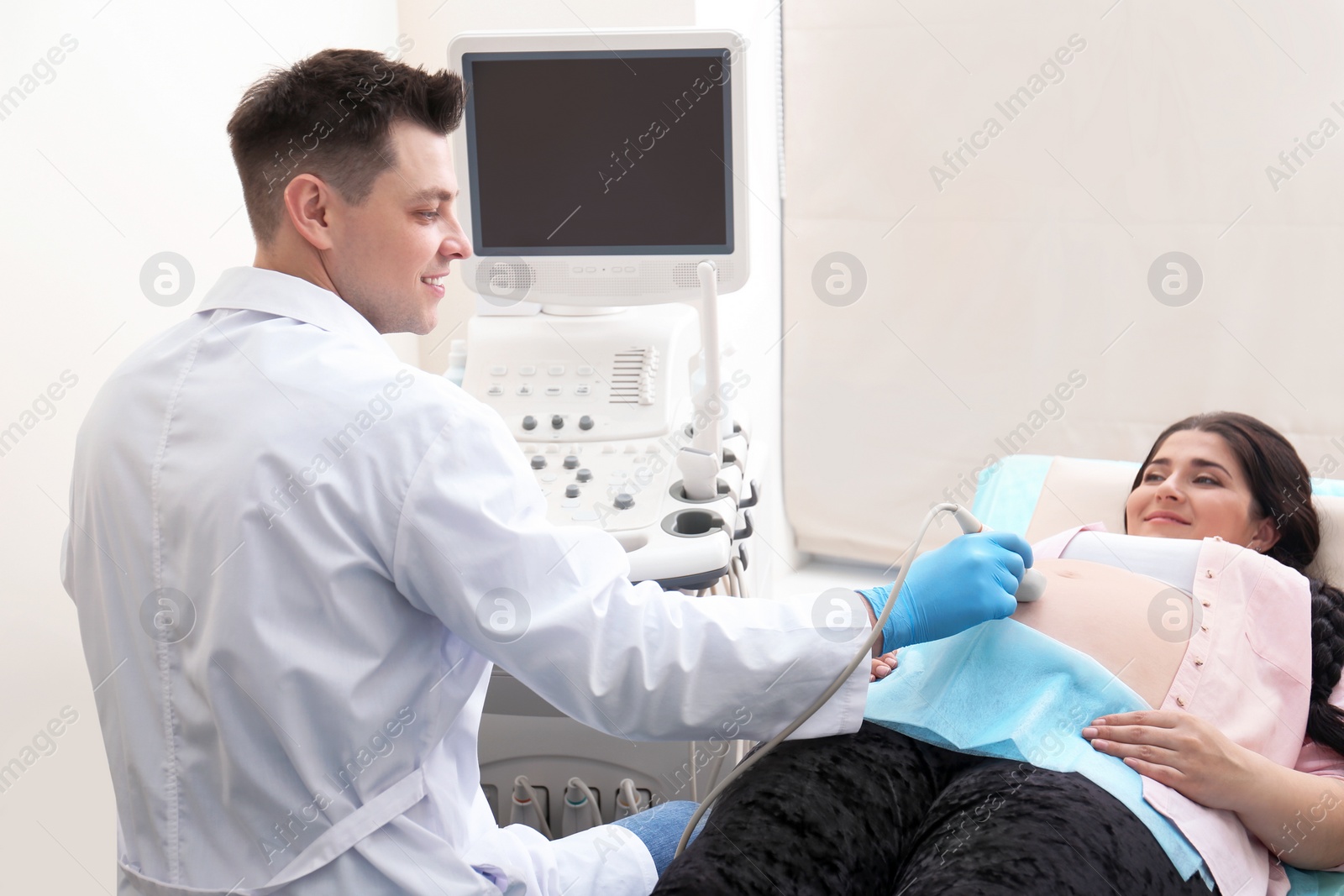 Photo of Young pregnant woman undergoing ultrasound scan in clinic