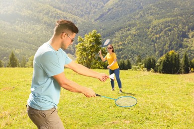 Couple playing badminton in mountains on sunny day