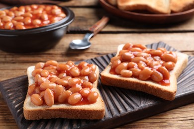 Photo of Toasts with delicious canned beans on wooden table