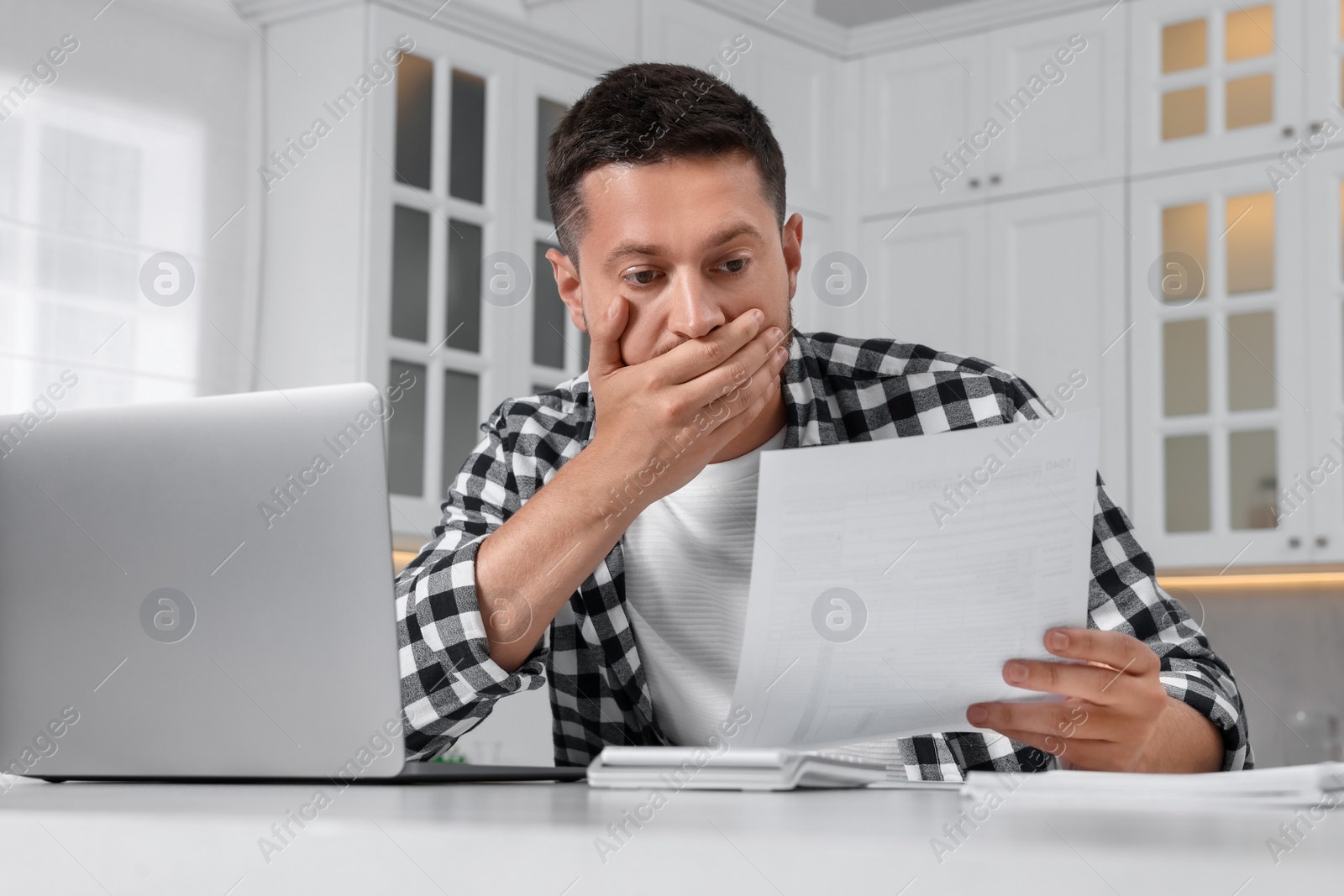 Photo of Man doing taxes at table in kitchen