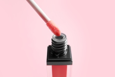 Applicator above liquid lipstick tube on color background