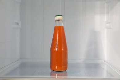 Photo of Bottle of juice on shelf inside modern refrigerator