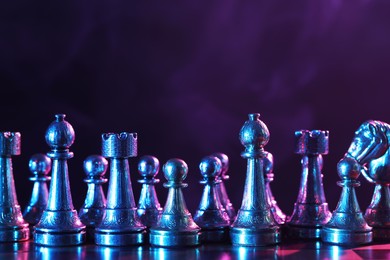 Photo of Chess pieces on checkerboard in color light. Space for text