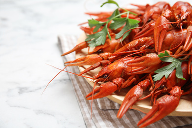 Delicious boiled crayfishes on white marble table, closeup. Space for text