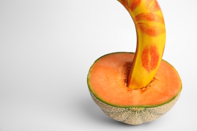 Photo of Fresh banana with red lipstick marks and melon on white background. Sex concept
