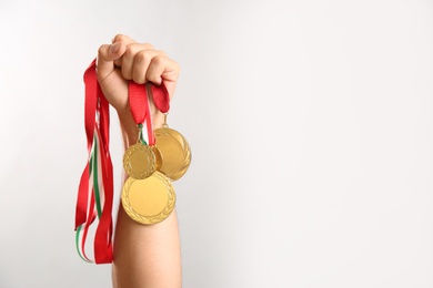 Photo of Man holding golden medals on grey background, closeup. Space for design