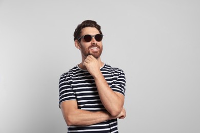 Photo of Portrait of smiling bearded man with stylish sunglasses on grey background