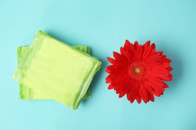 Photo of Flat lay composition with menstrual pads and gerbera flower on color background. Gynecological care