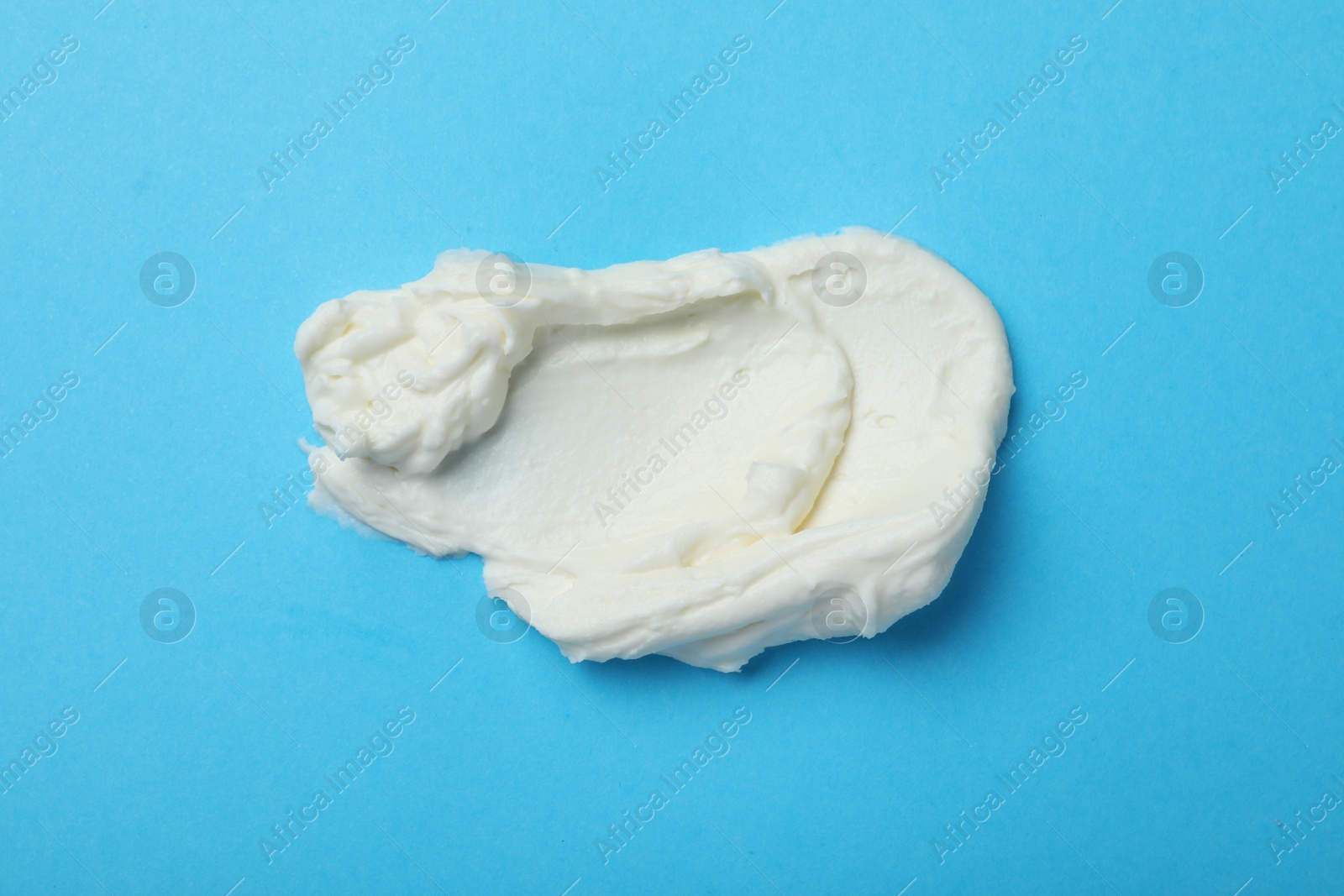 Photo of Smear of delicious cream cheese on light blue background, top view