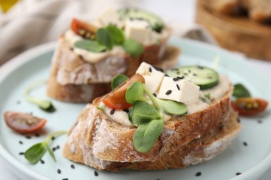 Tasty vegan sandwiches with tofu, cucumber, tomato and sesame seeds on plate, closeup