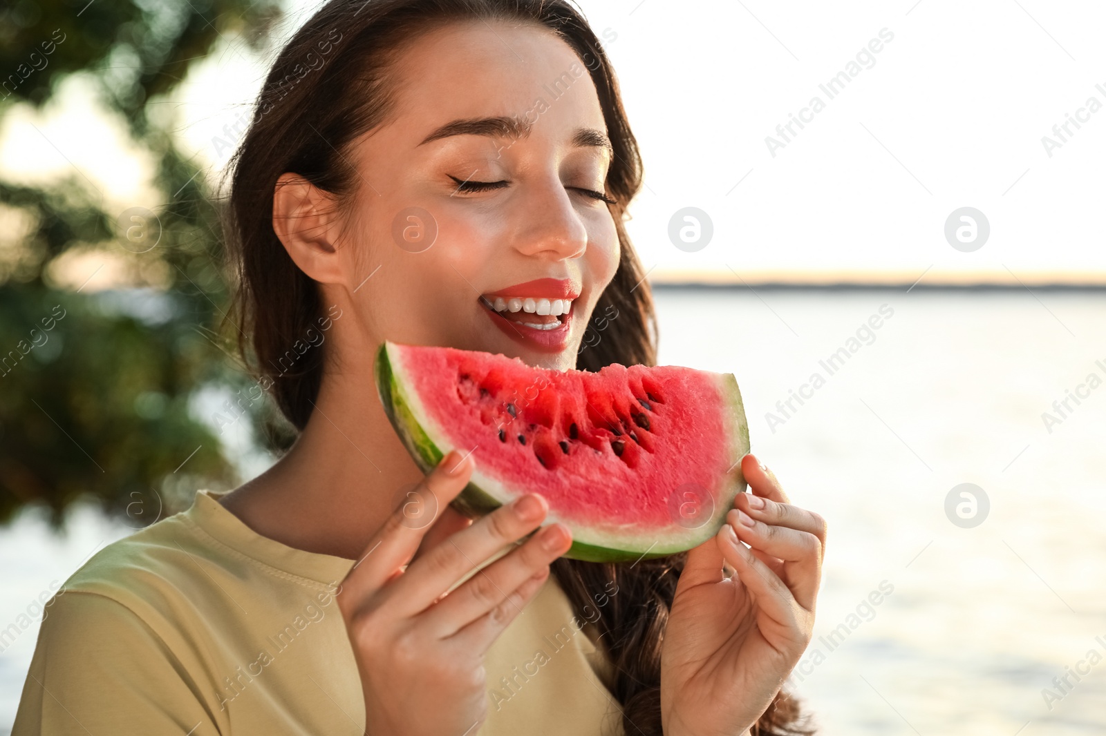 Photo of Beautiful young woman with watermelon near river