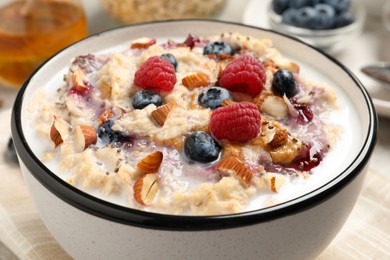 Tasty oatmeal porridge with toppings on table, closeup