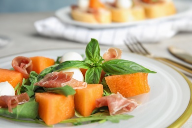 Photo of Fresh melon with prosciutto, mozzarella and basil on plate, closeup