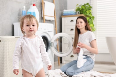 Photo of Little girl, baby clothes and mother in bathroom, selective focus