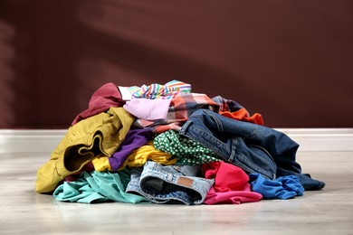 Photo of Pile of dirty clothes on floor near brown wall indoors