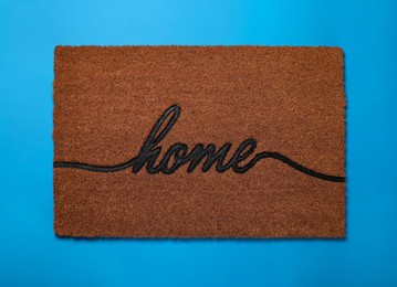 Doormat with word Home on light blue background, top view