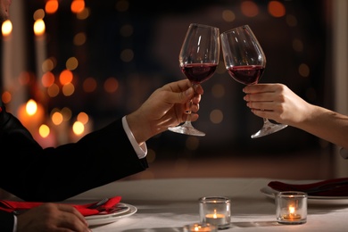 Photo of Couple clinking glasses at Valentine's day dinner in restaurant, closeup