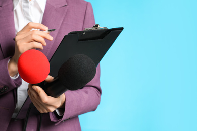 Professional journalist taking notes on light blue background, closeup. Space for text