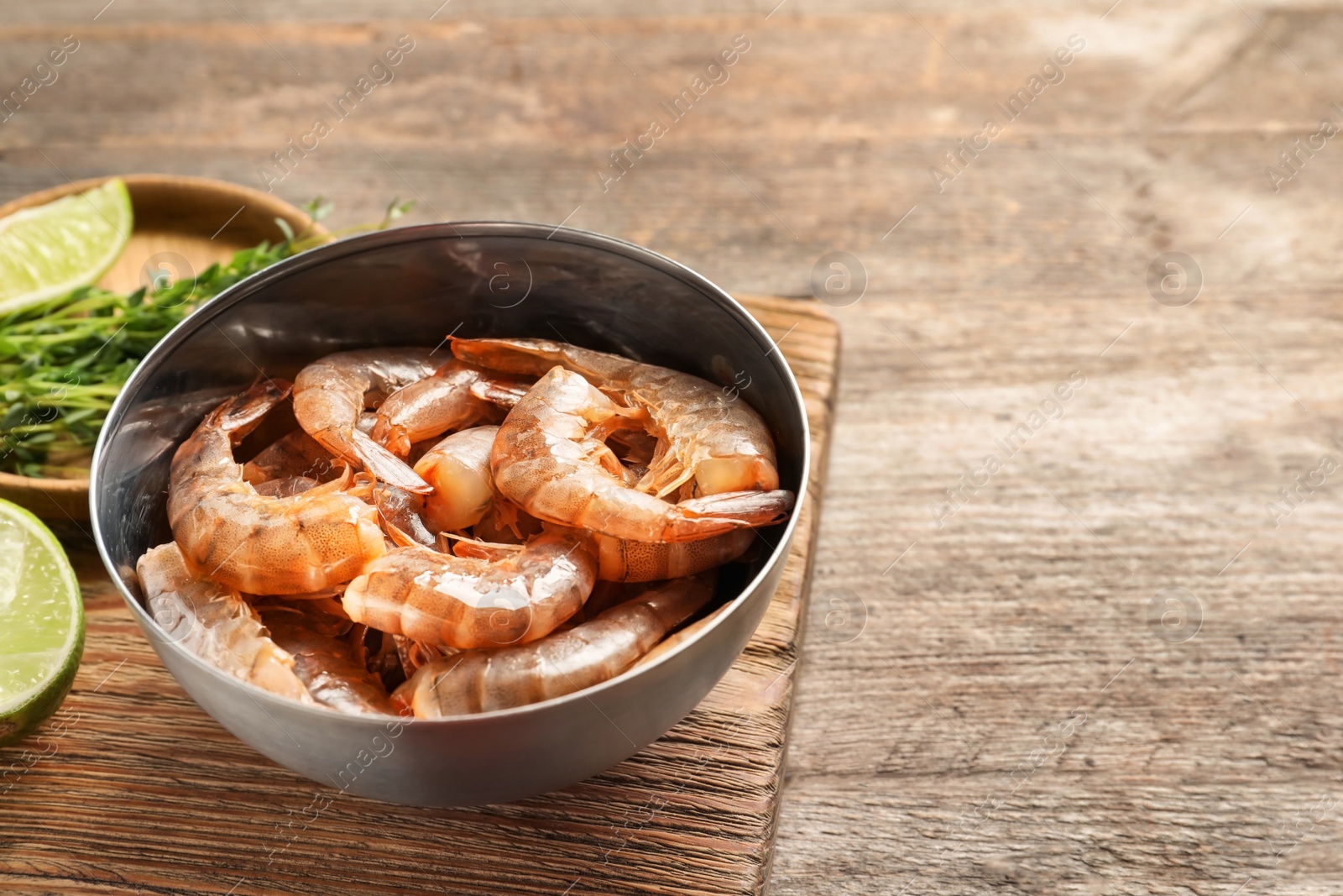 Photo of Bowl with fresh shrimps on wooden board