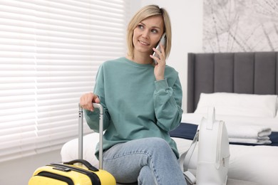 Smiling guest talking on smartphone in stylish hotel room