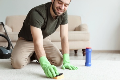 Young man cleaning carpet at home