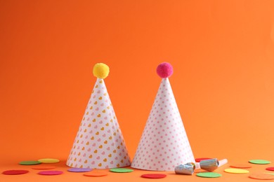 Party hats and other bright decor elements on orange background