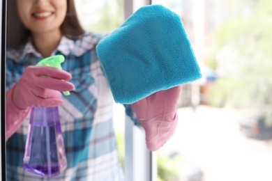 Young woman cleaning window glass at home