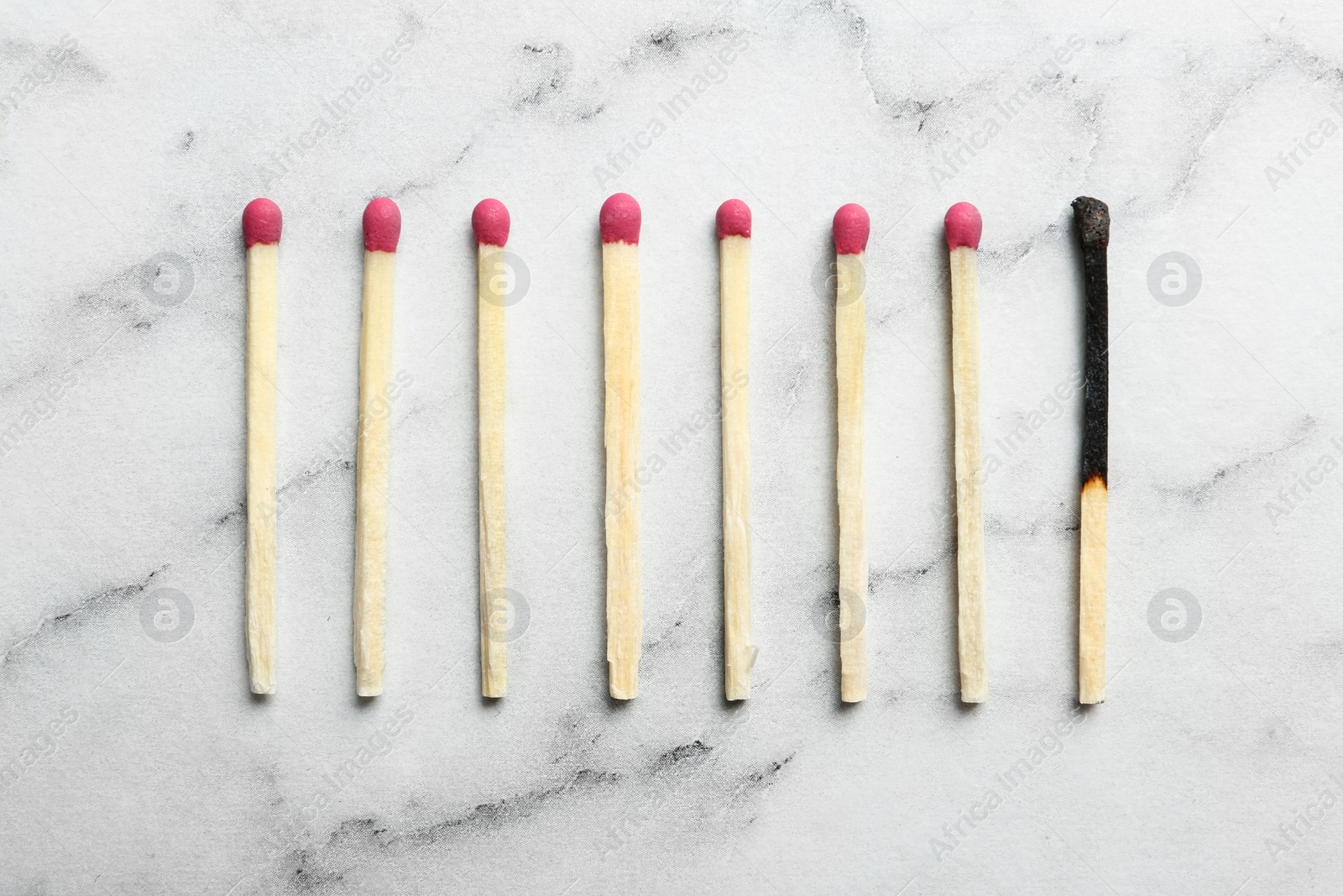 Photo of Used match among whole ones on marble background, flat lay. Psychological burnout concept