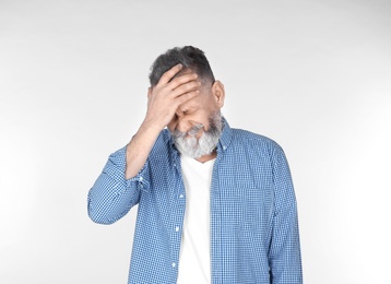 Man suffering from headache on light background