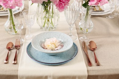 Stylish table setting with beautiful peonies and golden cutlery