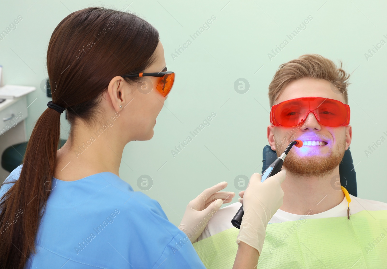 Photo of Professional dentist working with patient in modern clinic. Teeth whitening